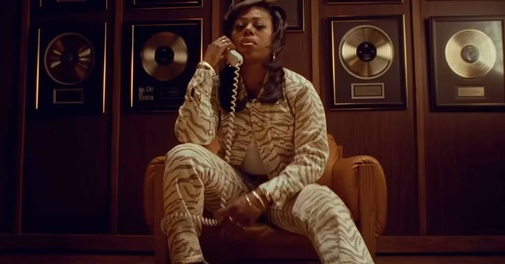 The Drop Season 1 Episode 3 Explained image showing Wanda on the phone inside the record label surrounded by gold records.