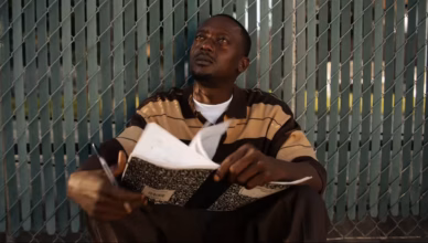 The Drop Season 1 Episode 7 Explained – Artillery sits against a chain-link fence holding a notebook and pen as he reflects on Keith's murder, his musical ambitions and the struggle to escape gang violence in “Blood In, Blood Out.”